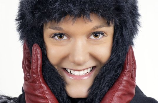 Winter time: portrait of smiling friendfly natural young woman wearing black faux fur hat with red leather gloves.