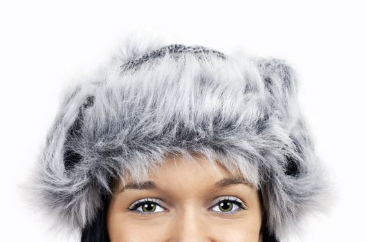 Fun winter time theme: close up on the green eyes of a smiling friendfly beautiful young woman wearing grey faux fur hat.