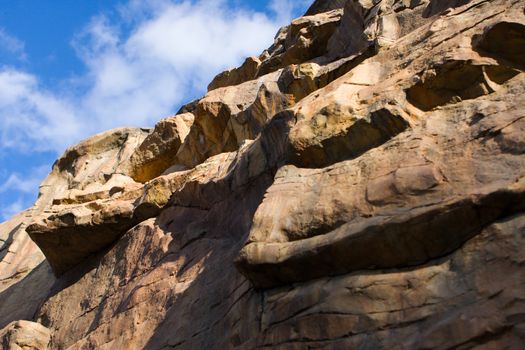 A vertical Cliff wall and fair sky.