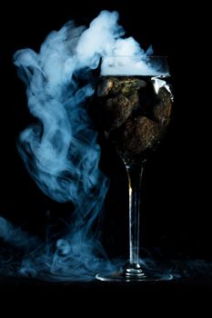 Smoking wine glass with lava rocks.