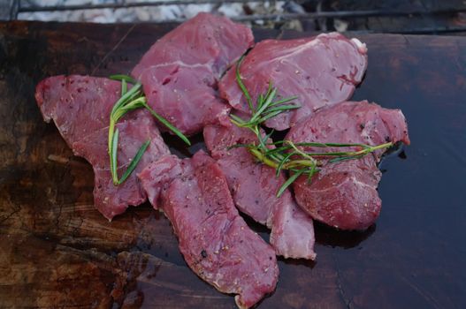 deer meat on bbq flagstone with rosemary