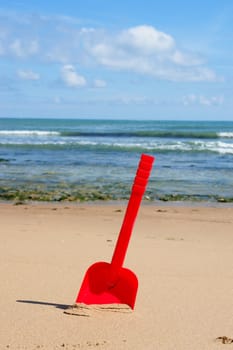 a red shovel at the beach on a sunny day