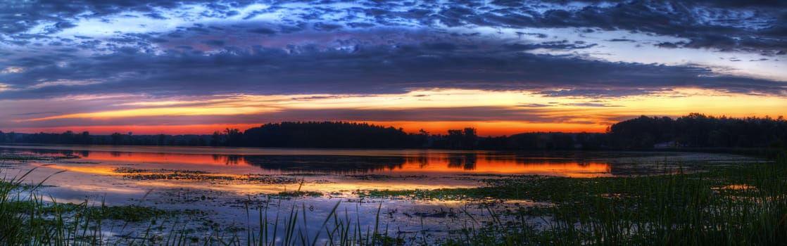 Panorama of a beautiful sunrise on a lake.