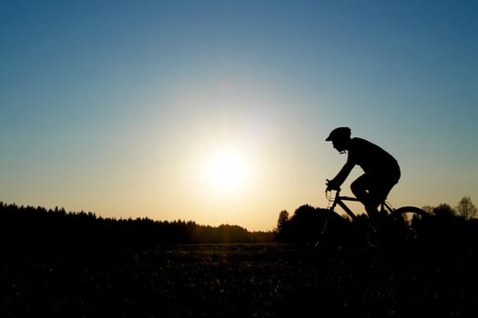 biker on a meadow at the sunset