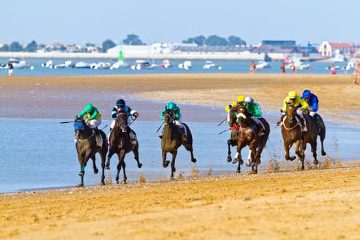 SANLUCAR DE BARRAMEDA, CADIZ, SPAIN - AUGUST 10: Unidentified riders race horses on Sanlucar de Barrameda beach on August 10, 2011 in Sanlucar de Barrameda, Cadiz, Spain.