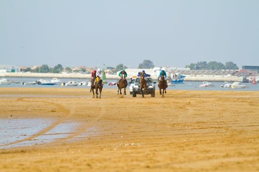 SANLUCAR DE BARRAMEDA, CADIZ, SPAIN - AUGUST 11: Unidentified riders race horses on Sanlucar de Barrameda beach on August 11, 2011 in Sanlucar de Barrameda, Cadiz, Spain.