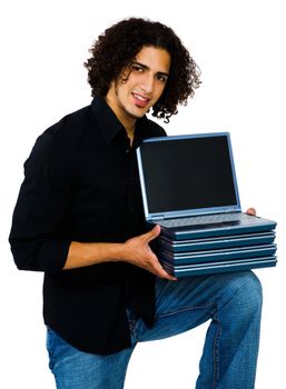 Smiling man holding a stack of laptops and posing isolated over white