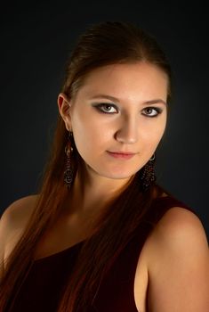 Portrait of young woman with red hair on dark background