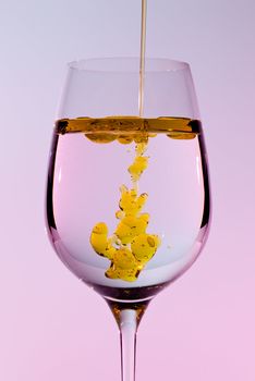 Olive oil being poured into a large wine goblet forming golden bubbles in the liquid