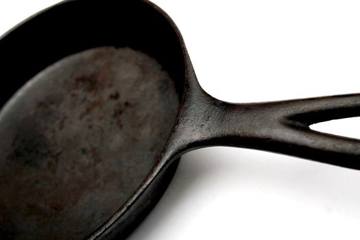 a black, well-seasoned cast iron frying pan on a white background