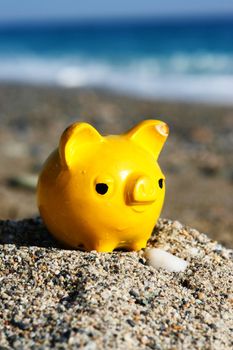 close up of a yellow piggybank on the beach