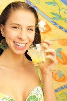 A young and sexy lady in swimsuit drinking juice on a hot day