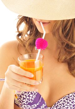 A young and sexy lady in swimsuit and hat under drinking juice on a hot day