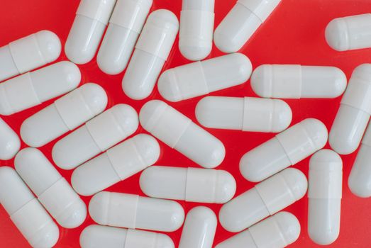 Macro view of white pills on red background.