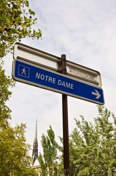 Index "Notre Dame De Paris" on the background of the spire of the cathedral. Summer daylight. Paris, city space