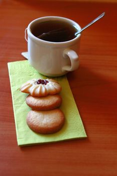 cup of hot tea with sweet cookies on the table