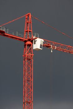 Red tower crane against dark overcast sky