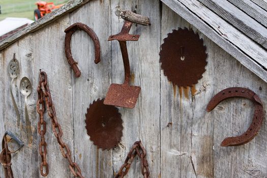 Antique farm tools hanging on the wall of a shed.