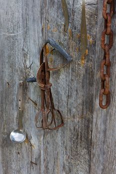 Rusty Hand Mixer and Chain hangs on a farm wall.