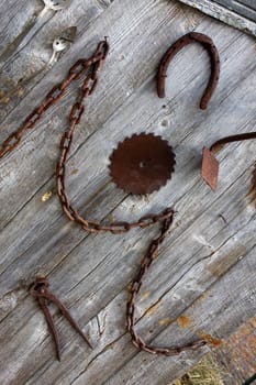 An old shed wall with antique farm tools hanging on it.