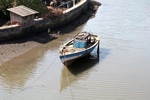 An empty fishing boat on an Indian riverbank.