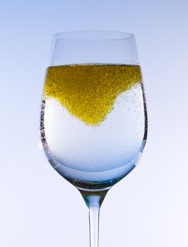 Olive oil being stirred in a large wine goblet forming golden bubbles in the liquid