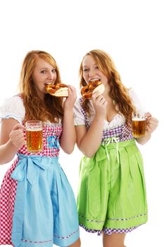 two bavarian dressed women with beer eating pretzels on white background