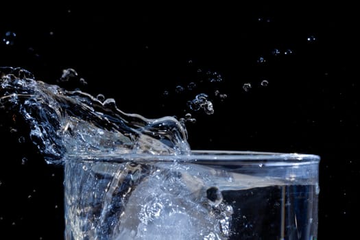 The motion of ice splashing into a glass of water frozen in time