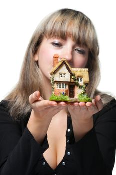 The business woman holds the small house in the hands. Focus on the house. It is isolated on the white background.