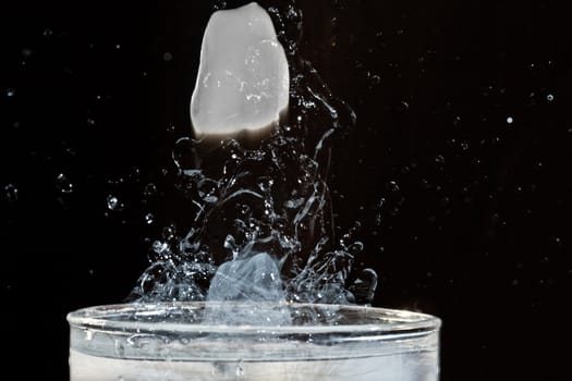 The motion of ice splashing into a glass of water frozen in time