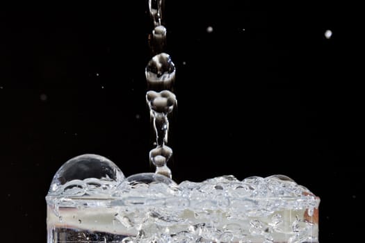 Water dripping into a glass of water forming bubbles