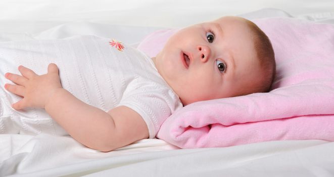 The baby lays. Age of 8 months. It is isolated on a white background