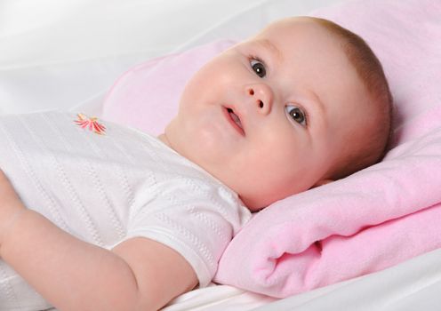 The baby lays. Age of 8 months. It is isolated on a white background