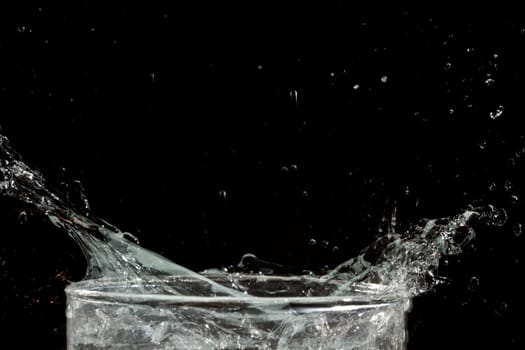The motion of ice splashing into a glass of water frozen in time