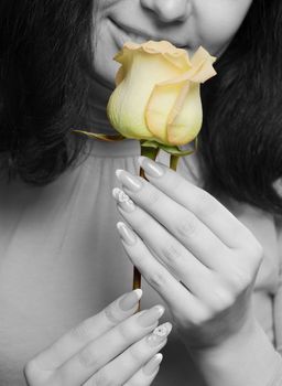 The woman with a yellow rose close up. The monochrome image of the woman and a color rose