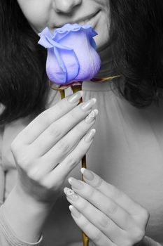 The woman with a blue rose closeup. The monochrome image of the woman and a color rose