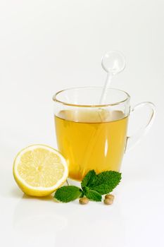 Glass of hot tea with peppermint on bright background