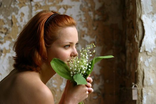 Portrait of the girl with flowers on a background of an old wall