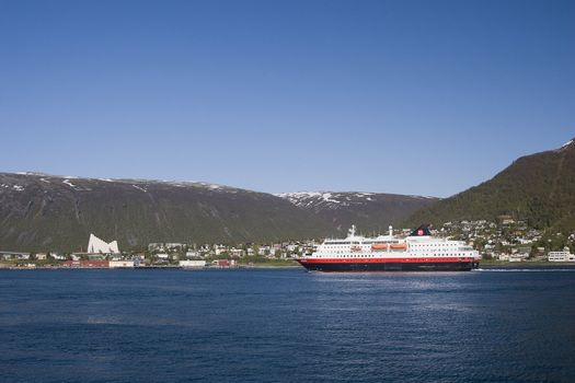 The hurtigruten ship in Tromso, Norway. You can see the city's landmark behind the boat, illustrating Troms and tourism very well. 