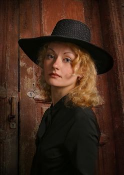 Portrait of attractive lady in a hat on a background of an old door