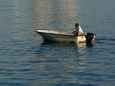 A man motoring across a harbor in his boat.