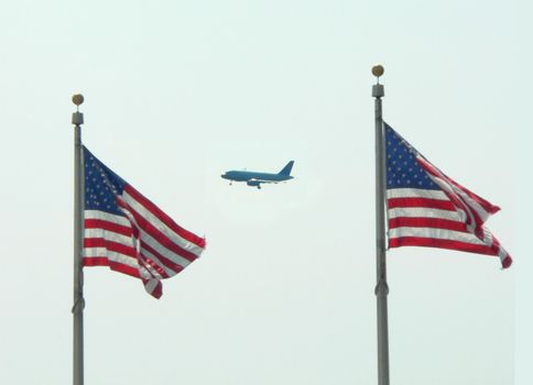 An airliner flying between two flags.