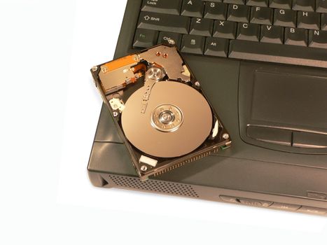 A laptop hard drive sitting on top of the laptop.  