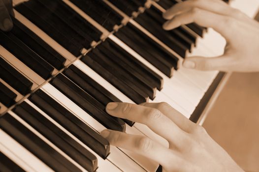 Hands above keys of the piano. A photo close up.Old color