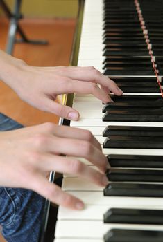 Hands above keys of the piano. A photo close up.