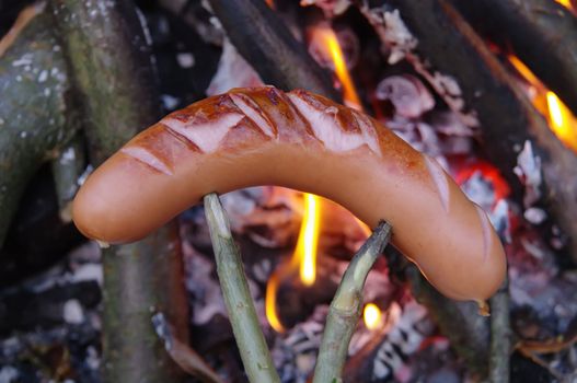 a sausage grilled on a camp fire