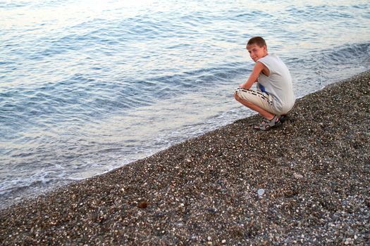 youth sits in summer on the shore sea