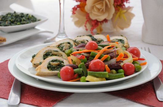 Sliced chicken roll with spinach and mushrooms garnished with vegetables
