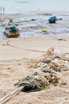 Rope tied to a fishing boat on the beach near the ocean in view.