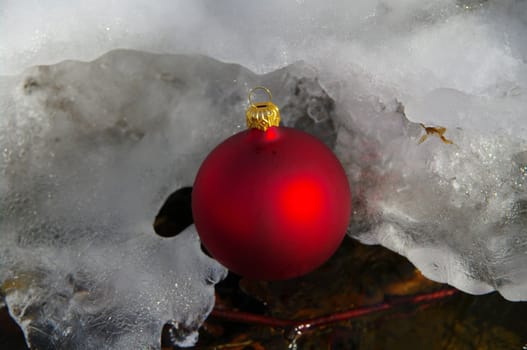 red bauble on a real snowy icy surface